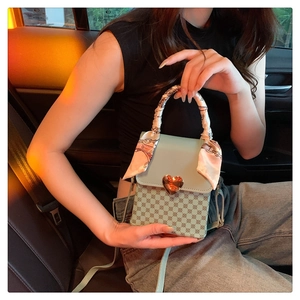 Detail of mint green crossbody bag with golden heart lock and decorative silk ribbon scarf