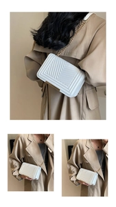 Close-up of white quilted chain bag with V-shaped stitching and gold metal buckle detail