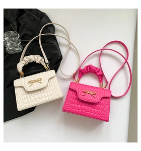 Detail of crossbody bag with metal bow buckle and pleated handle in white and rose pink