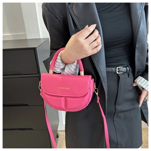 Detalle de bolso bandolera semicircular rosa fucsia con letras doradas y herrajes
