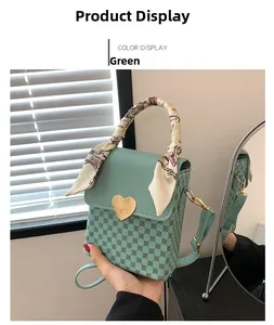 Detail of green plaid crossbody bag with heart-shaped metal clasp and silk scarf handle