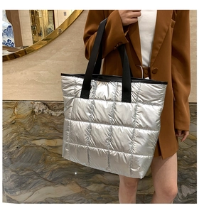 Détail d'un sac cabas argenté matelassé avec sangle noire porté par un mannequin