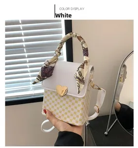 Detail of white leather handbag with floral pattern, heart lock and silk scarf handle