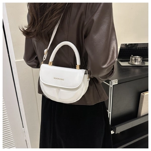 Bolso bandolera de media luna blanco con diseño geométrico llevado por una modelo