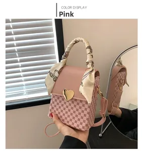 Detail of pink plaid handbag featuring a golden heart lock and silk scarf handle