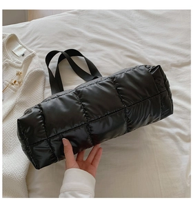 Gros plan d'un sac cabas matelassé noir sur tissu blanc avec accessoires de mode