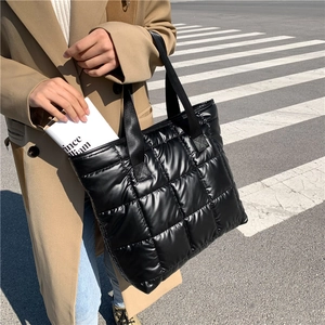Photo street style d'un grand sac cabas matelassé noir en nylon brillant pour femme