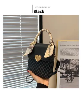 Detail of black crossbody bag with gold heart lock and decorative printed silk ribbon
