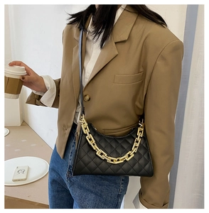 Détail de la texture matelassée et de la grosse chaîne dorée sur un sac baguette noir