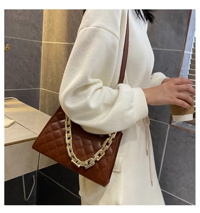 Détail d'un sac à bandoulière matelassé marron foncé avec une chaîne dorée élégante