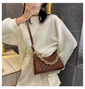 Sac bandoulière marron matelassé avec chaîne dorée porté sur un ensemble blanc