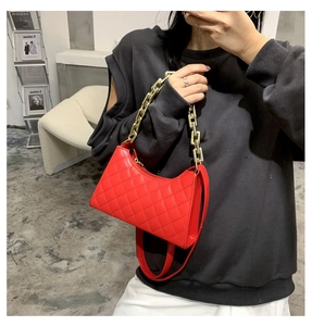 Détail du sac rouge en similicuir matelassé avec une poignée en grosse chaîne dorée
