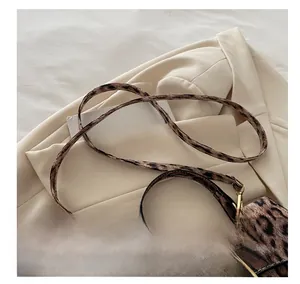 Close-up of leopard print handbag showing golden metal buckle and adjustable shoulder strap