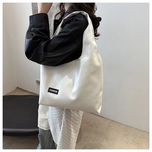 Detailed side view of white PU leather tote bag with black Fashion tag worn by model