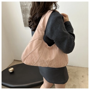 Detail of light pink hobo bag featuring pleated texture and radial stitching on faux leather