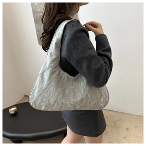 Detail of silver metallic pleated hobo bag showing wrinkled texture and chic curved design