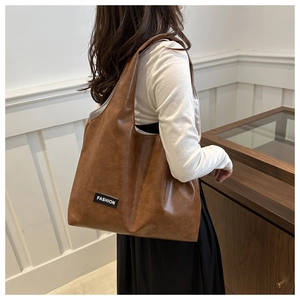 Detail of vintage brown tote bag with fashion label shown on a shoulder