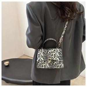 Detail of grey leopard print handbag with golden metal twist lock and plush texture