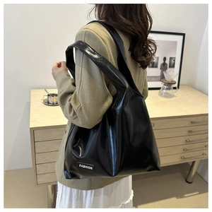 Close-up of black glossy PU leather tote bag with a white Fashion brand label