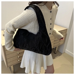 Detailed view of a black crescent underarm bag with soft textured material on a model