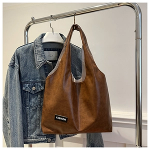 Detail of dark brown oil wax leather tote bag featuring a black Fashion label tag