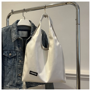 Detail of white leather tote bag with a woven Fashion label on the bottom corner