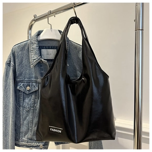Close-up of black glossy oil wax leather tote bag with FASHION label on a metal hanger