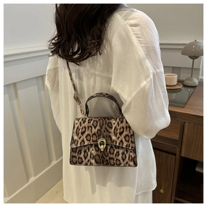 Chic leopard print crossbody bag with gold buckle clasp on a white linen outfit background
