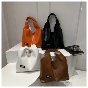 Close-up of four fashion tote bags in glossy oil wax leather with trendy label detail