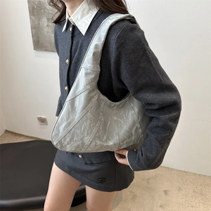 Minimalist silver hobo bag with wrinkled leather texture shown on model shoulder