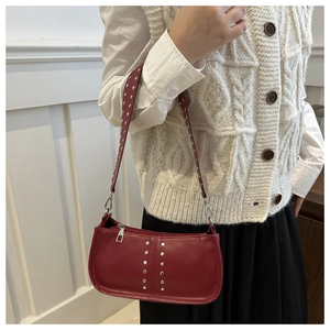 Détail du sac à bandoulière en cuir rouge avec clous argentés et fermeture éclair métal