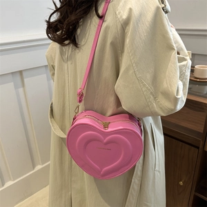 Pink heart-shaped crossbody bag with embossed logo and adjustable strap for women