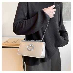 Close-up of silver mirror finish rectangular bag with crystal buckle and chain strap