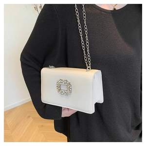 Detail of white square crossbody bag with sparkling crystal buckle and silver chain strap