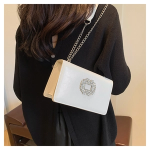 Detail of white PU leather crossbody bag with sparkling rhinestone buckle and chain strap
