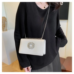Close-up of cream PU leather small square bag with oversized sparkling rhinestone buckle