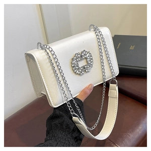 Detail of white leather shoulder bag featuring a luxury crystal-encrusted square buckle