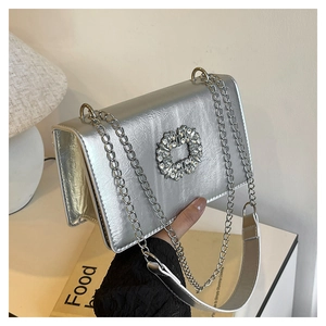 Detail of silver chain strap and sparkling rhinestone buckle on a mini square bag