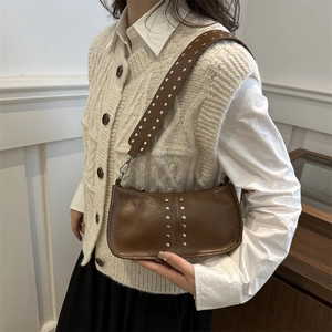 Sac bandoulière vintage marron avec clous argentés et large sangle sur le modèle