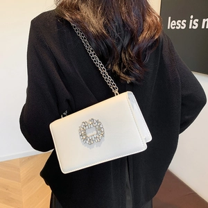 White minimalist crossbody flap bag with a circular rhinestone buckle and silver chain