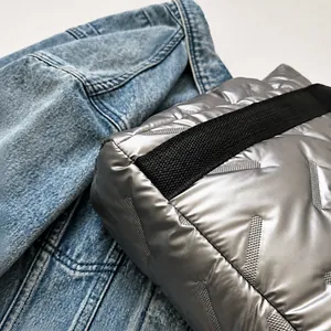 Detail of silver quilted tote bag with geometric stitching and black woven strap