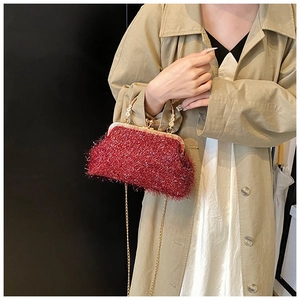 Détail du sac coquille bordeaux avec tissu pailleté, fermoir doré et anse perle