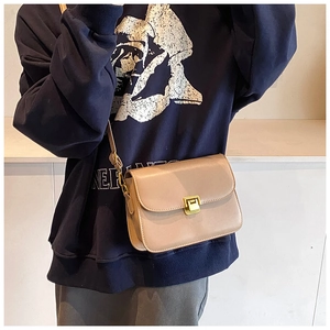 Detail of a chic apricot faux leather crossbody bag featuring a gold rectangular buckle