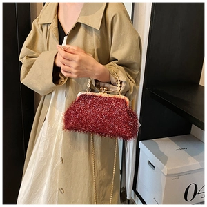 Gros plan du sac coquille bordeaux avec texture pailletée et poignée en métal doré