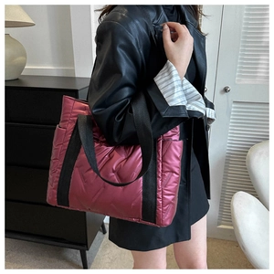 Details einer gesteppten Tragetasche in Metallic-Fuchsia mit schwarzem Canvas-Griff
