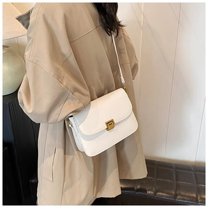 Detail of white leather crossbody bag with gold square buckle worn with khaki coat