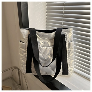 Detail der silbernen Stepp-Tote-Bag mit Metallic-Textur und schwarzen Webgriffen