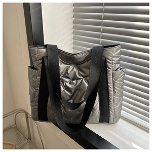 Detailansicht einer silbernen Stepptasche mit schwarzem Gurt auf einer Fensterbank