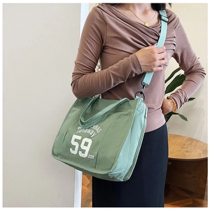 Detail of avocado green canvas tote with white letter print and adjustable shoulder strap
