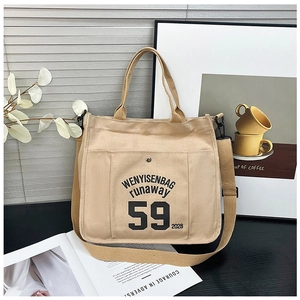Close-up of beige canvas tote bag with black typography print and snap pocket detail